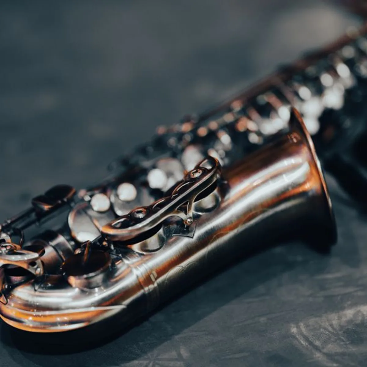 Close detail of a saxophone's brass body and keys in warm raking light.