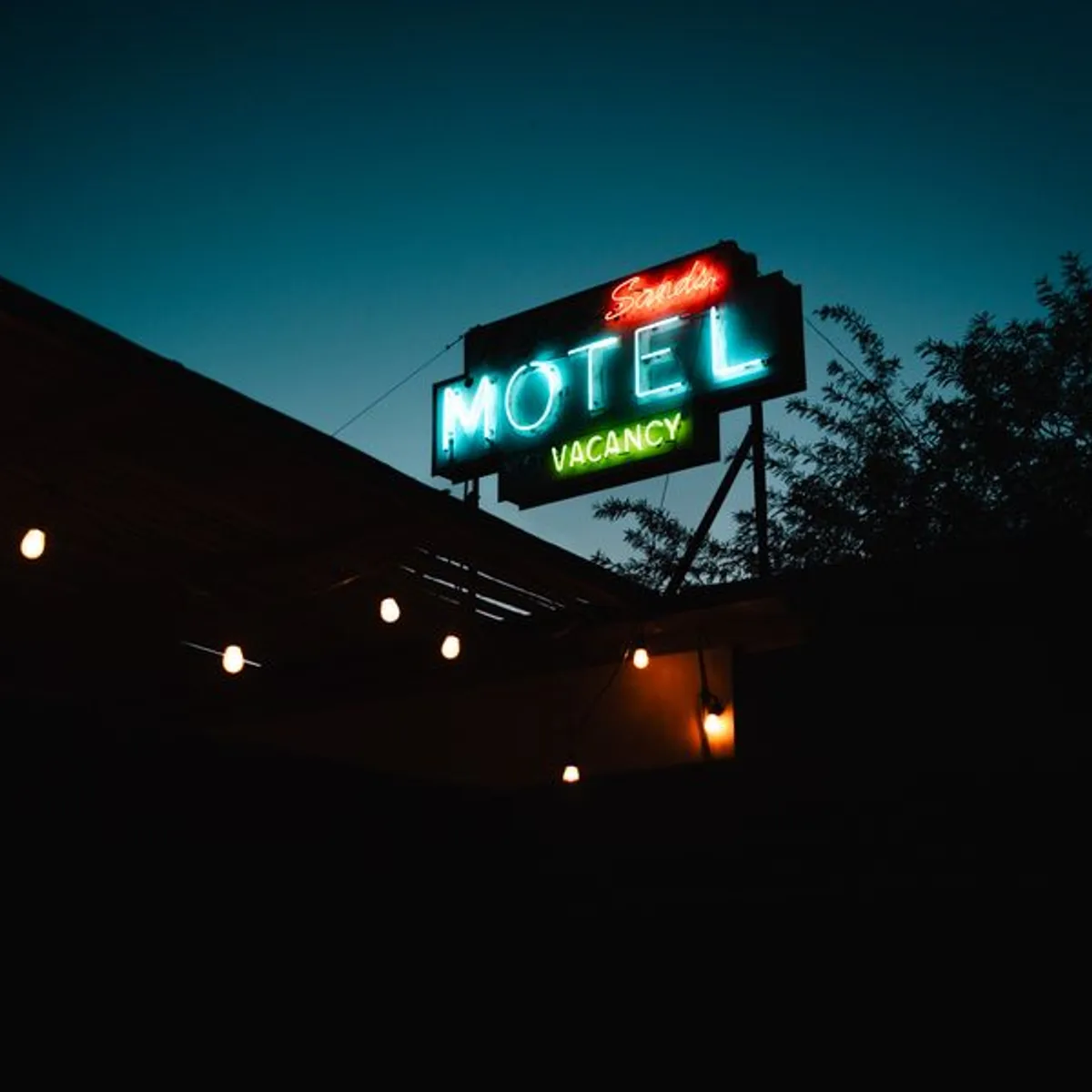 A lit motel sign against the dark mass of the building at dusk.