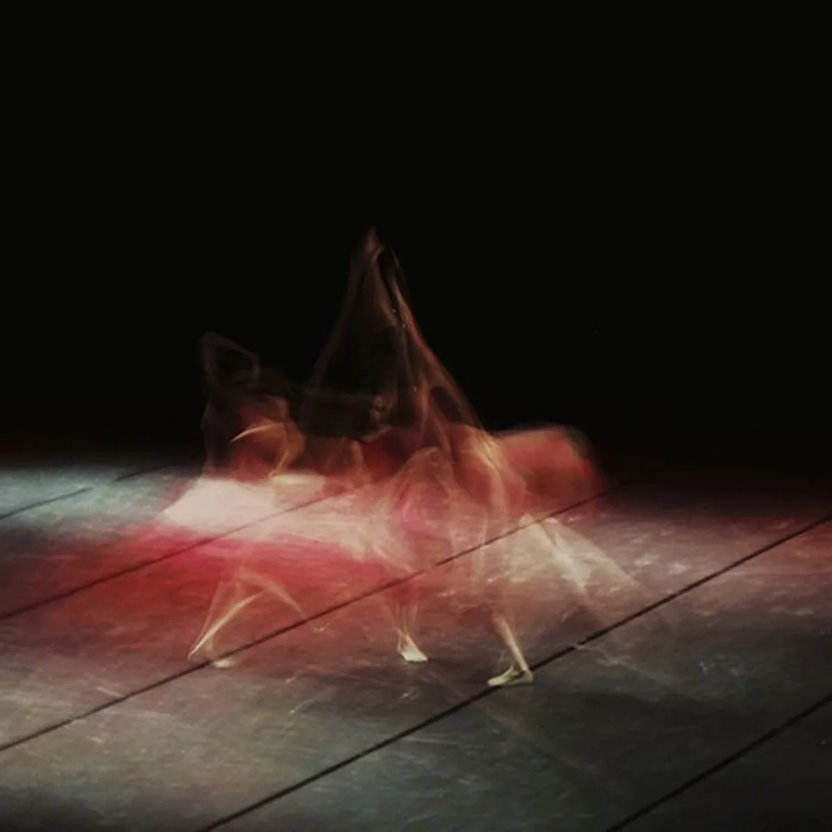 A dancer blurred by a long exposure on a dark stage.
